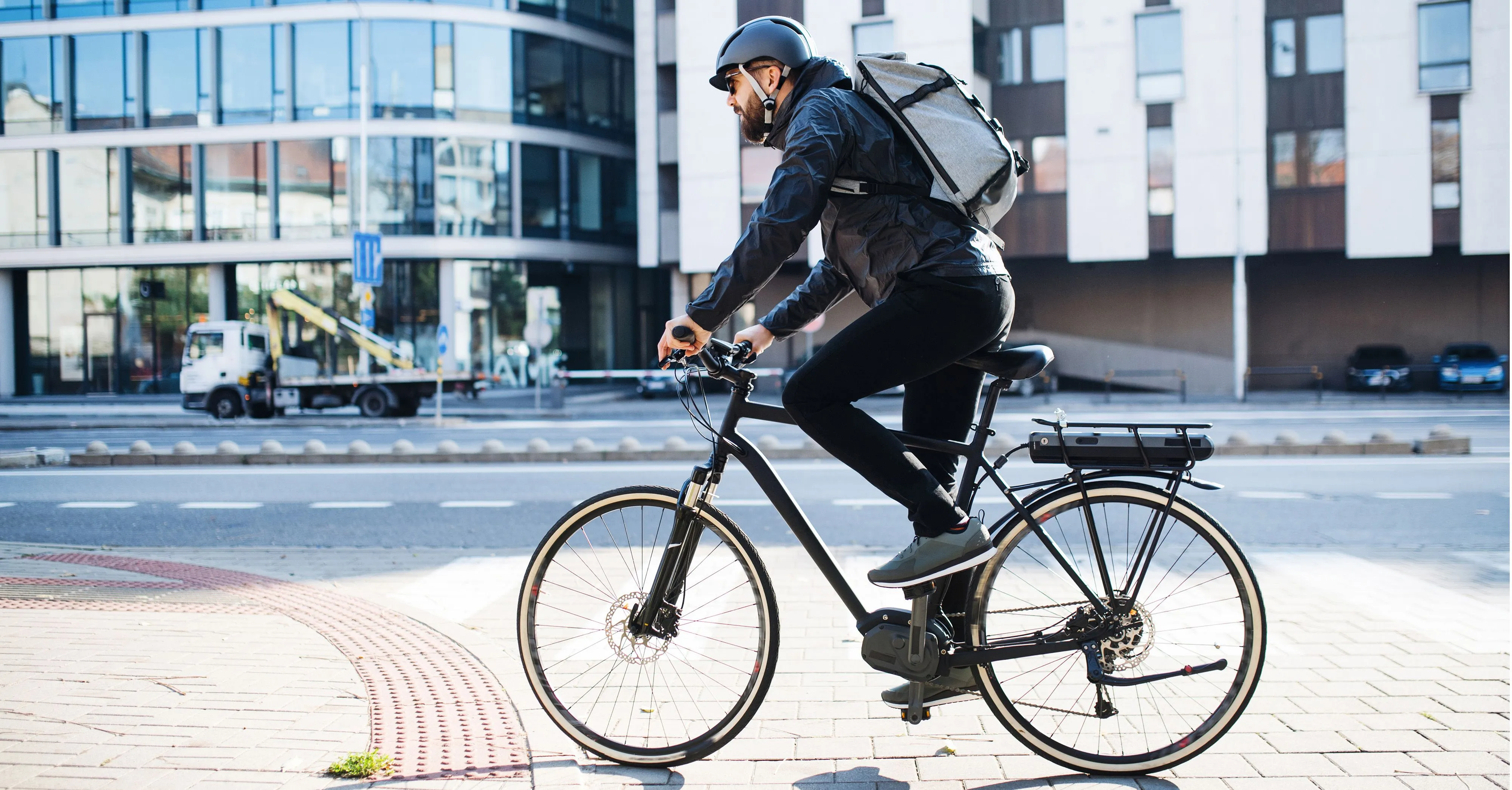 E-Bike-Fahrer in der Stadt mit passender Adam Riese Versicherung