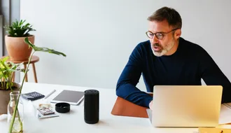 Man sitzt vor einem Laptop am Schreibtisch