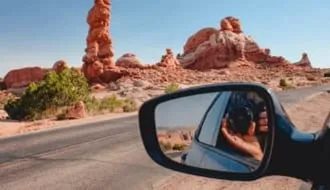 Mann im Auto fotografiert Wüsten-Natur-Kulisse.