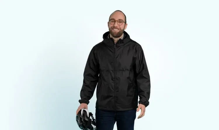 Mann mit Fahrradhelm in der Hand und Regenjacke an