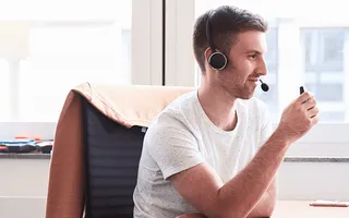 Volle Konzentration: Tobi am Schreibtisch mit Headset auf. Am Bildrand sieht man eine Kollegin sitzen.